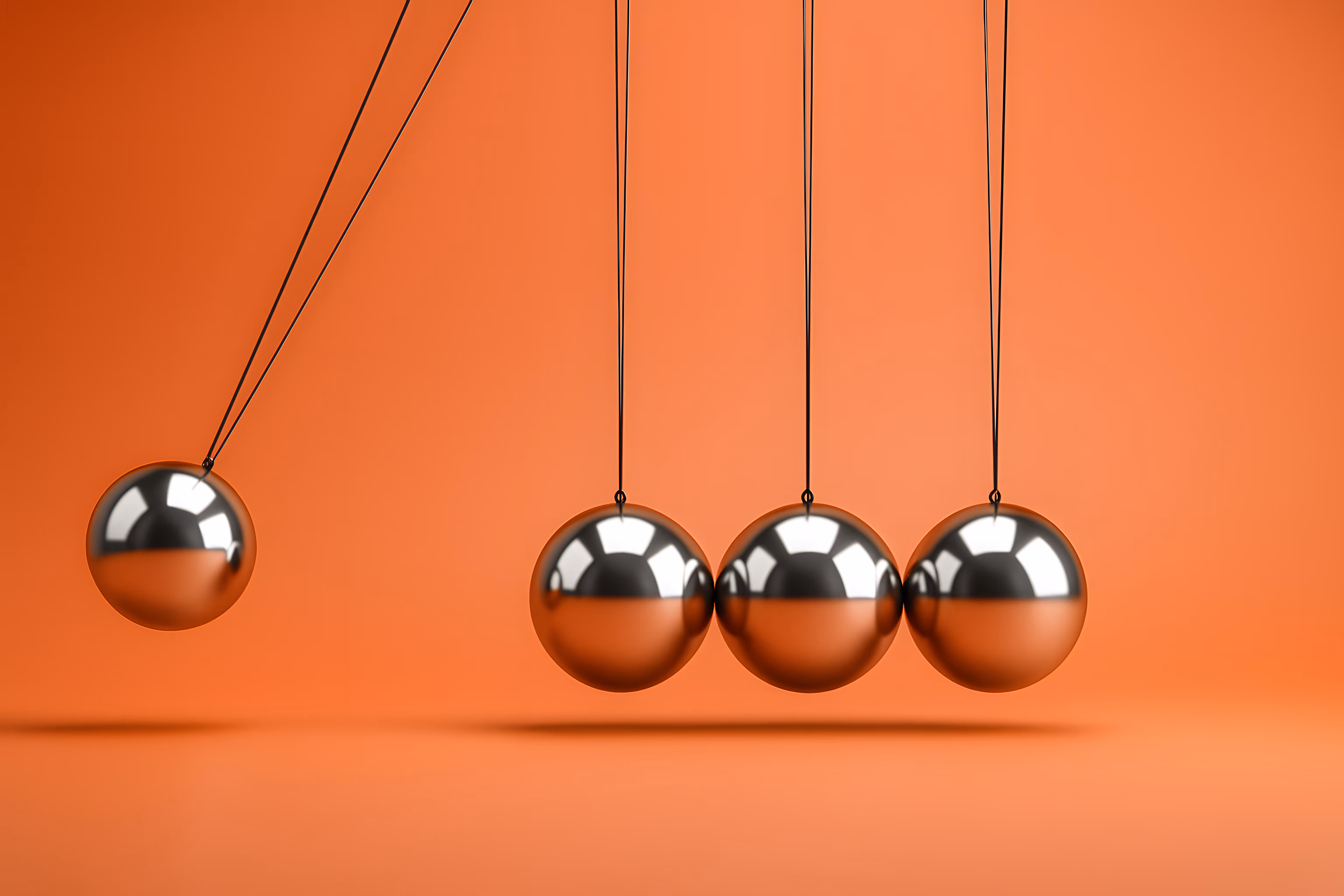 Newton's cradle with four steel balls suspended mid-swing against an orange background.