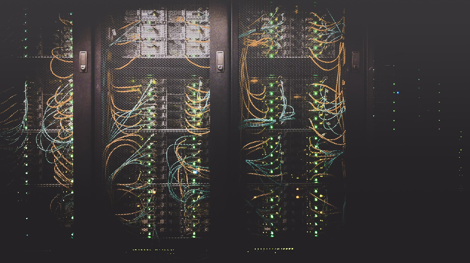 Server racks with network cables and green indicator lights behind protective mesh doors.